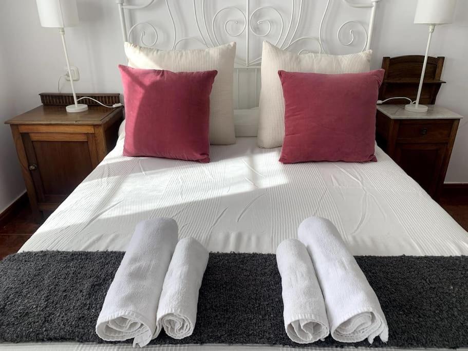 Una cama blanca con almohadas rojas y calcetines blancos. en Casa rural en Asturias, en Arboleya