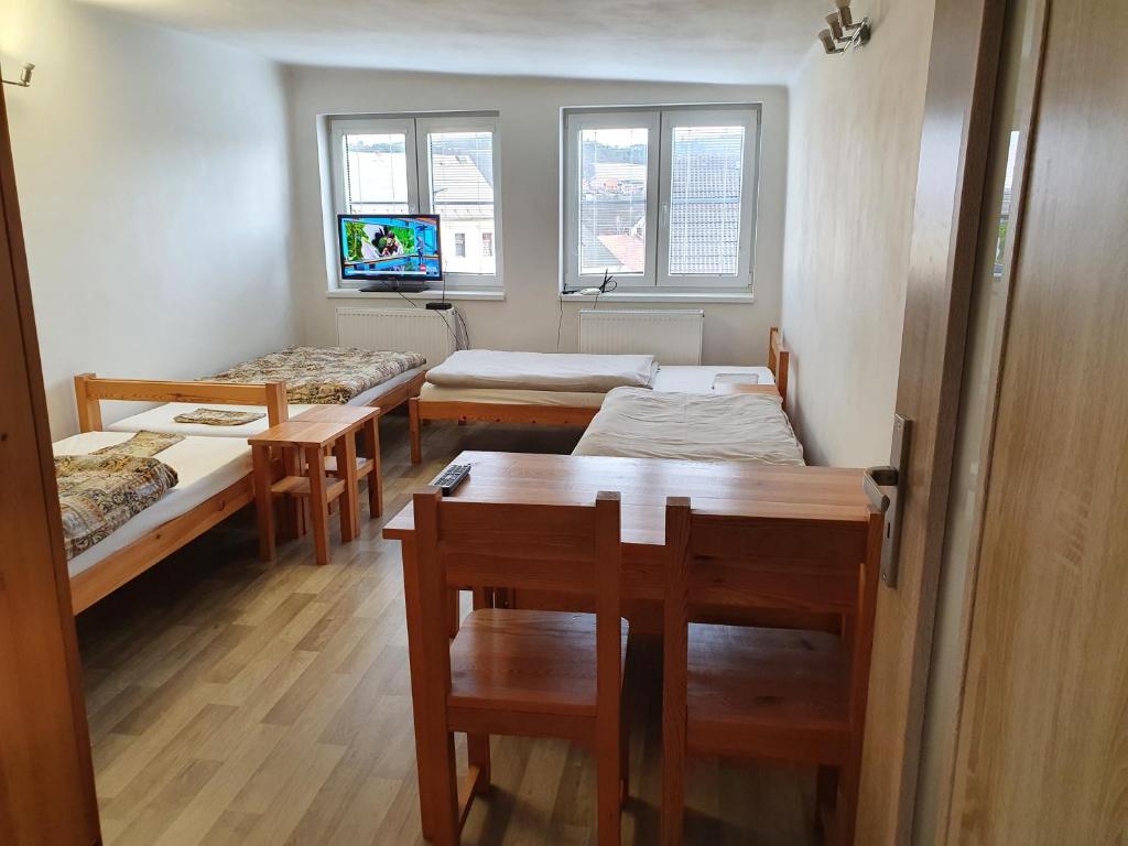 a room with three beds and a table and windows at Apartmán Plasy in Plasy