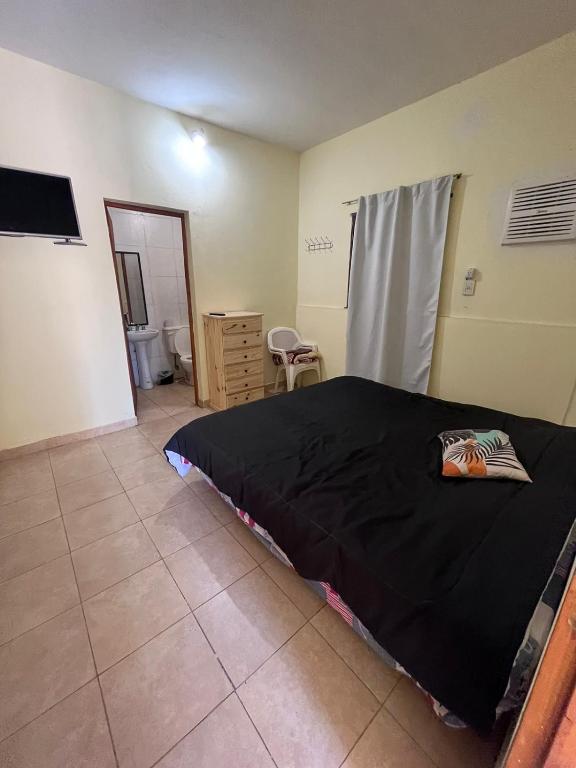 1 dormitorio con 1 cama con sábana negra en el suelo en La esquina en Santiago del Estero