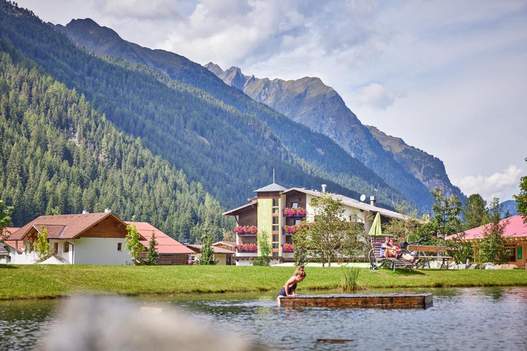 a person sitting in the water in front of a building at Bio Hotel Stillebach in Sankt Leonhard im Pitztal