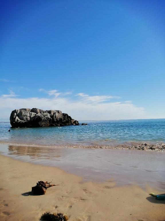 a beach with a large rock in the water at PENICHE - Guest House Casa das Estelas in Peniche