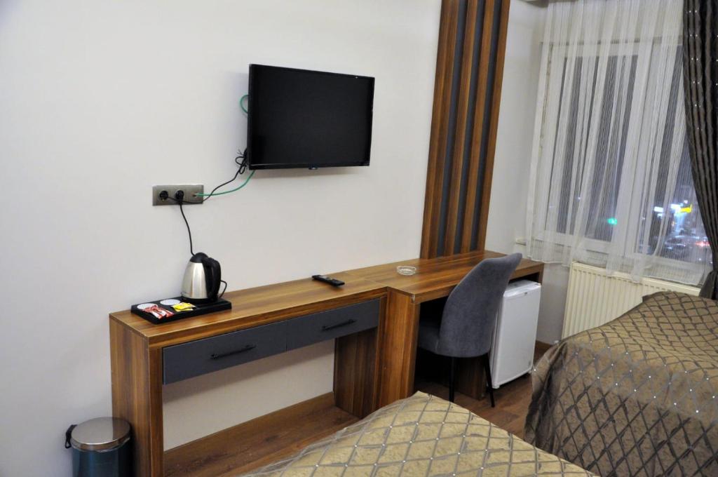 Habitación con escritorio y TV en la pared. en ERZURUM DAMAK GRUP, en Erzurum