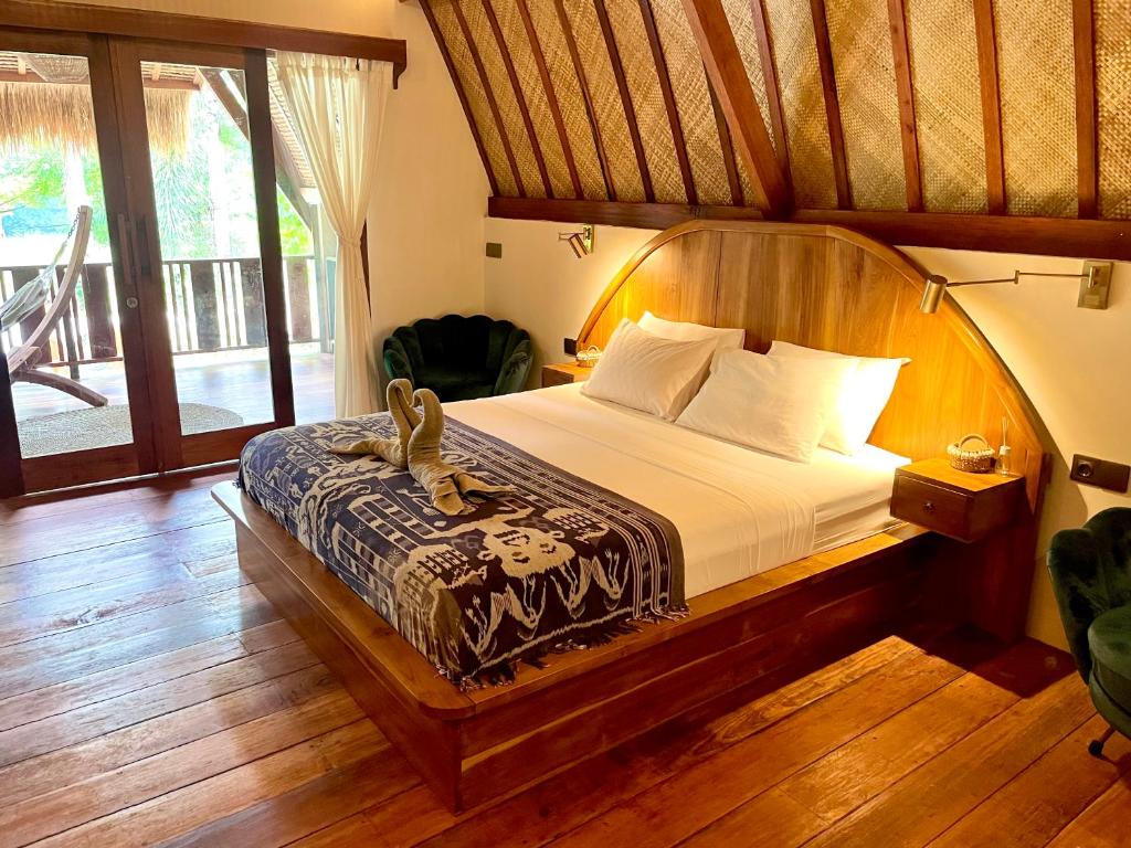 a bedroom with a large bed with a wooden headboard at La Villa Loca in Gili Air
