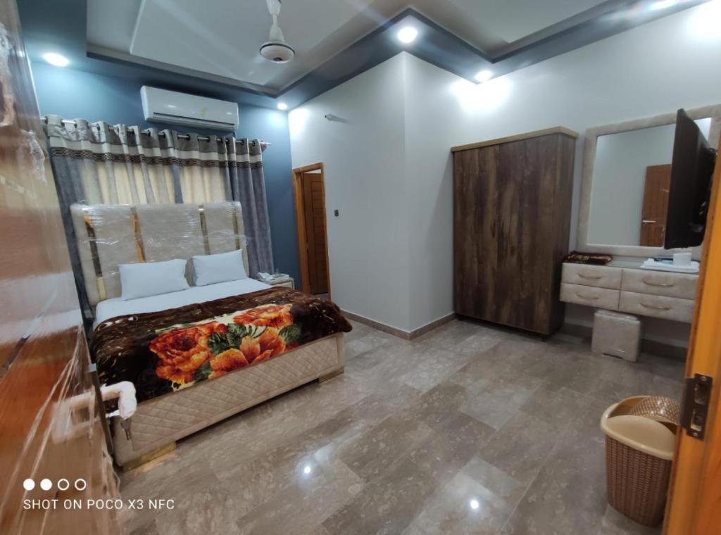 een slaapkamer met een bed en een badkamer met een wastafel bij Sk Travellers Inn in Karachi