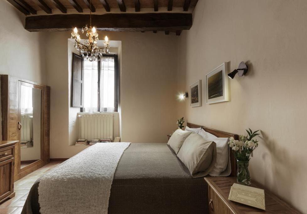 Schlafzimmer mit einem Bett und einem Kronleuchter in der Unterkunft PienzaLettings "Casa Olivieri" in Pienza