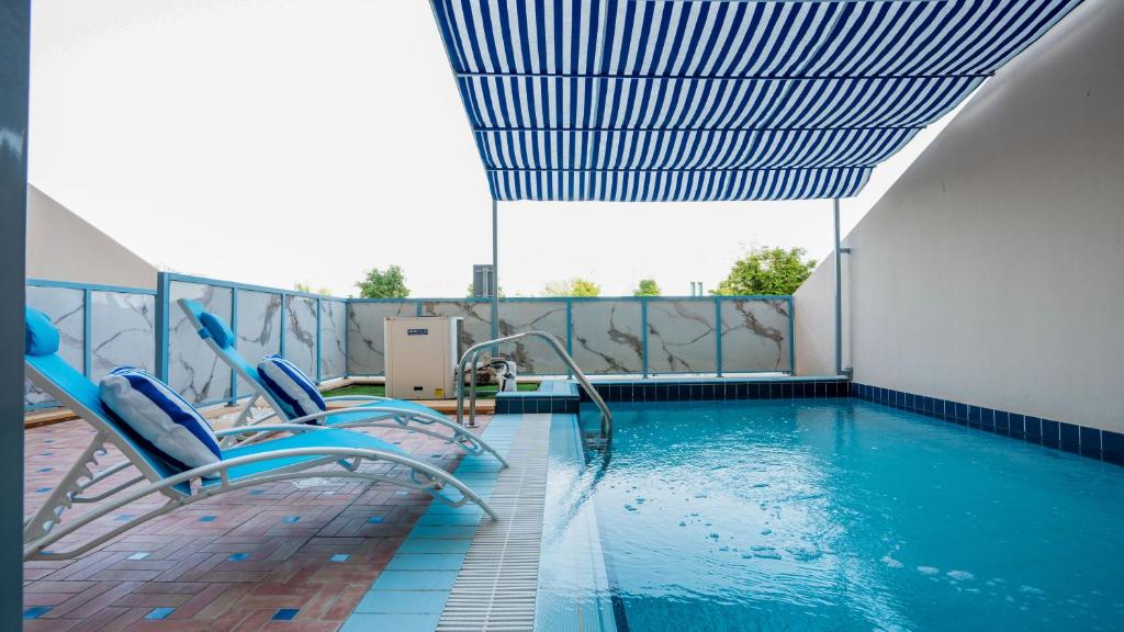 uma piscina com duas cadeiras ao lado de uma piscina em Exclusive Retreat GLOBALSTAY's New 3BR Townhouse with Private Pool no Dubai