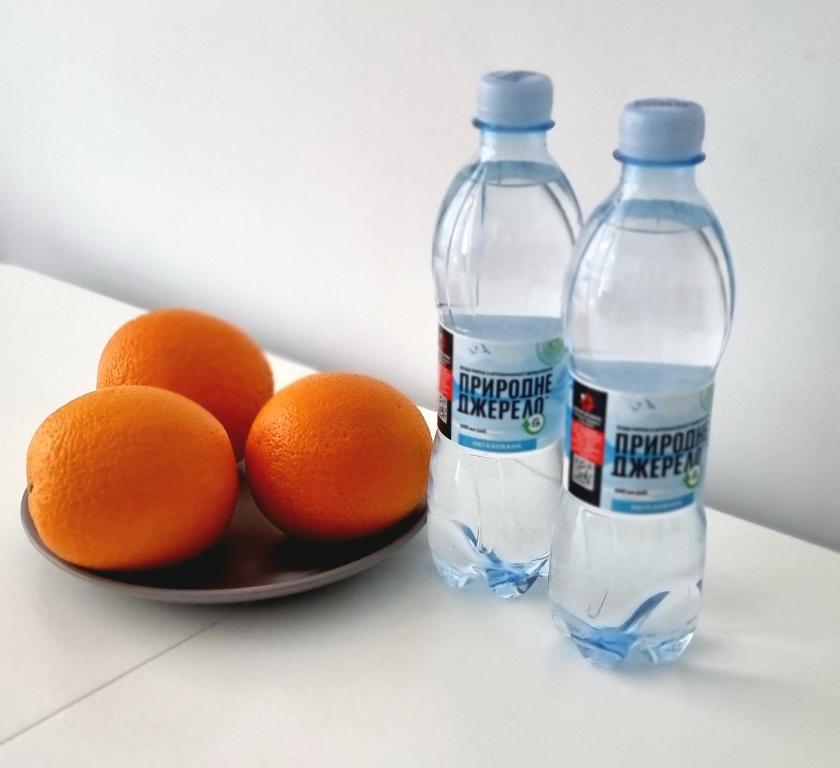 two bottles of water next to a plate of oranges at Центр Апарт in Ternopilʼ