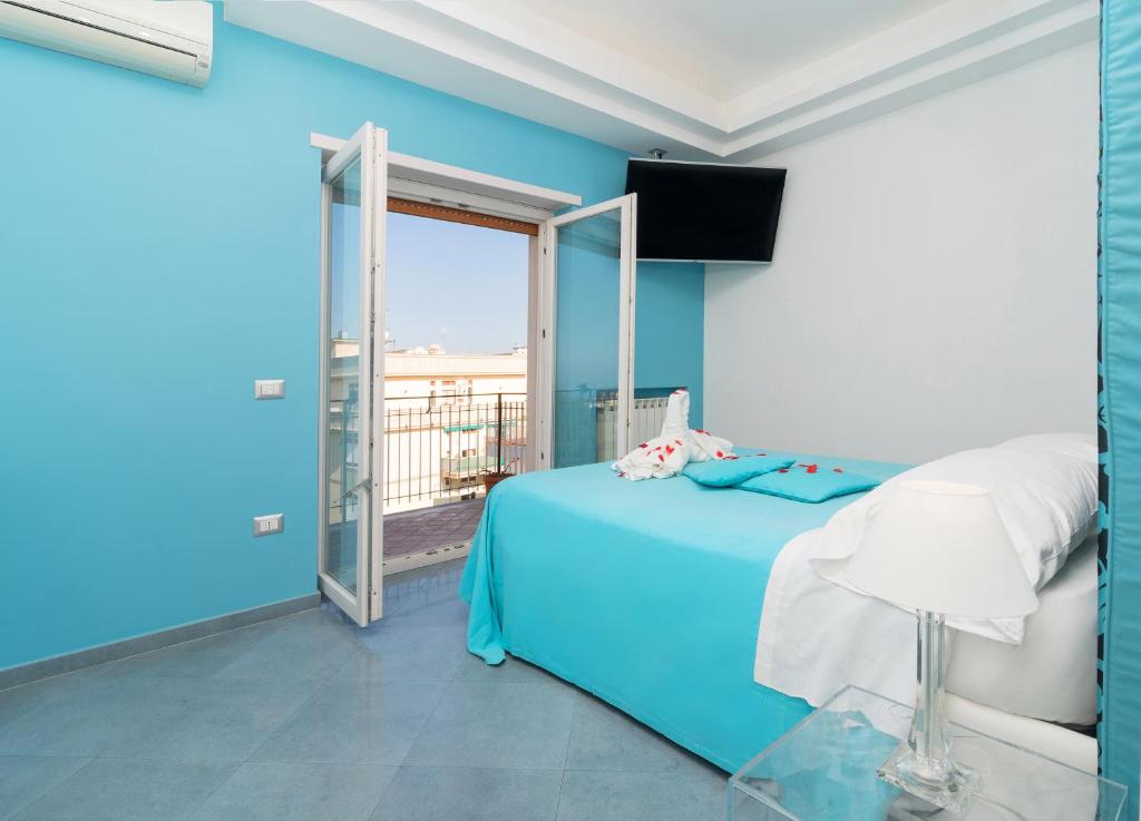 a blue bedroom with a bed and a balcony at Guest House Emily Suites Sorrento in Sorrento