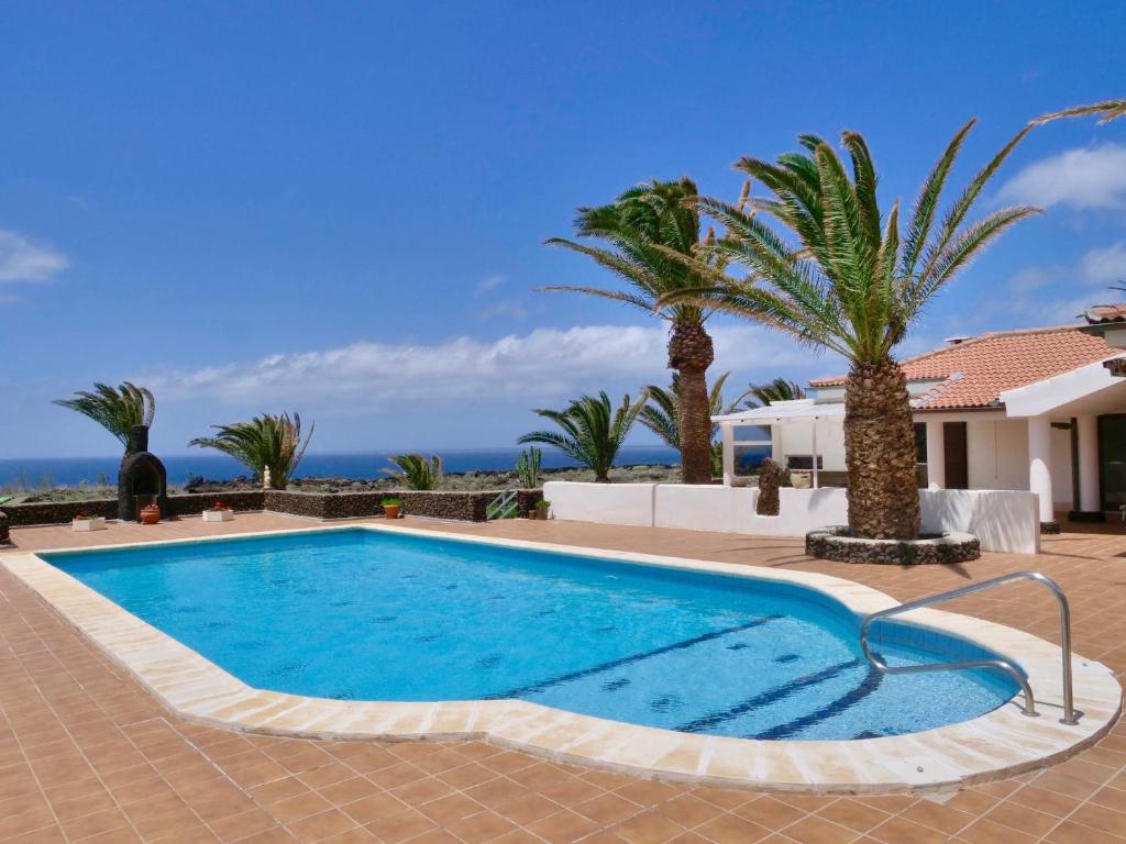una piscina con palmeras y el océano en Finca Afortunada en Las Puntas