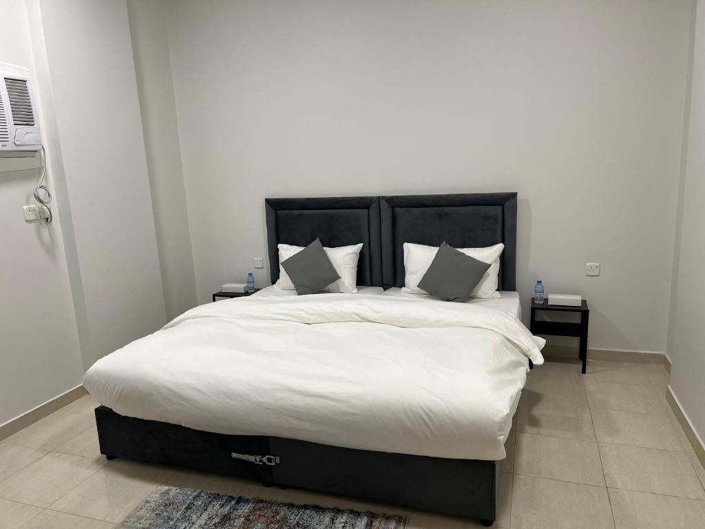 een slaapkamer met een groot bed met witte lakens en kussens bij الشقق الذكية in Yanbu