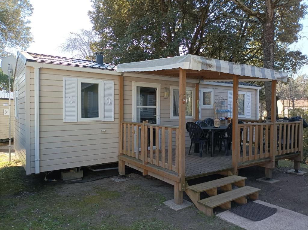 a large wooden cabin with a table on a deck at Beau Mobil home 64 in Saint-Jean-de-Monts