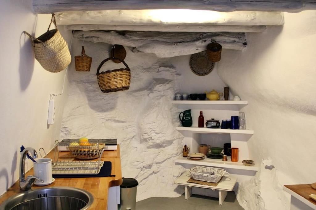 a kitchen with a sink and a stone wall at Thimari cottage in Andros in Agios Petros