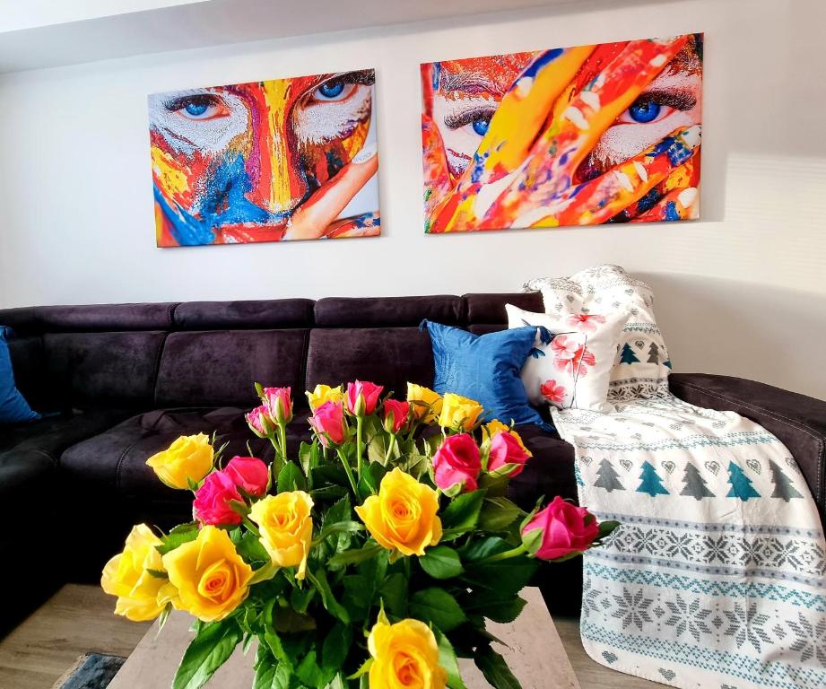 a living room with a couch with flowers and paintings at Apartament Jelonek w Karkonoszach in Jelenia Góra