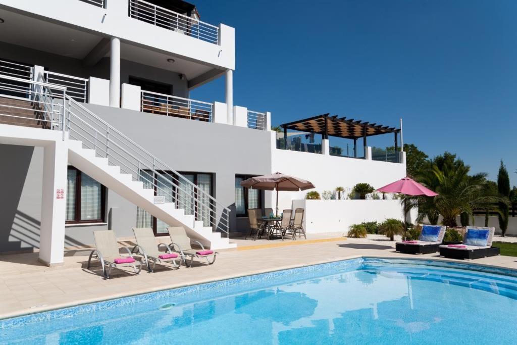 a villa with a swimming pool in front of a building at Villa Arcadia, Kallepia in Paphos