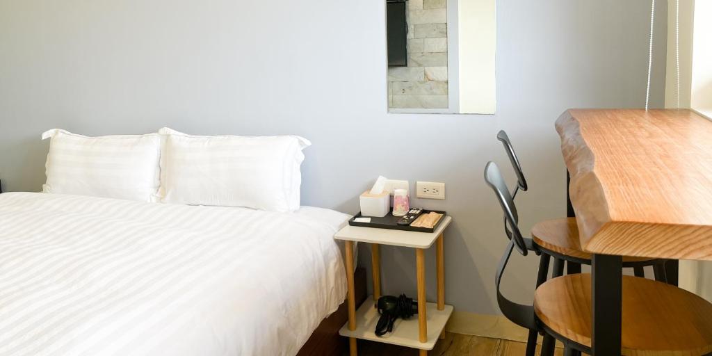 a bedroom with a bed and a table with a chair at Cen Pin B&amp;B in Jiufen