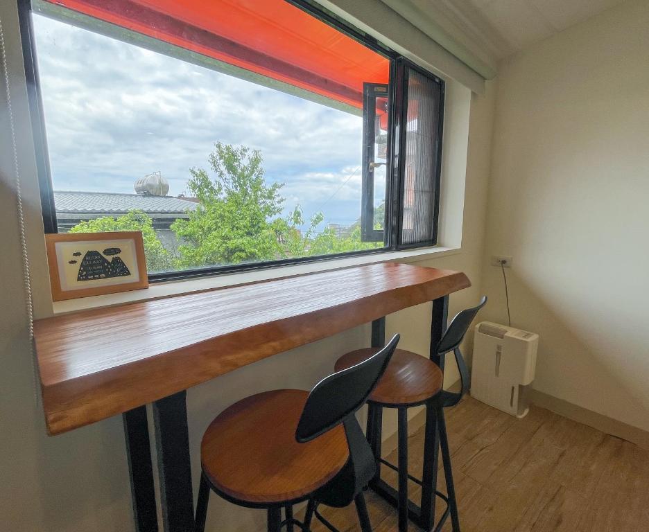 a bar with stools in front of a large window at Cen Pin B&amp;B in Jiufen