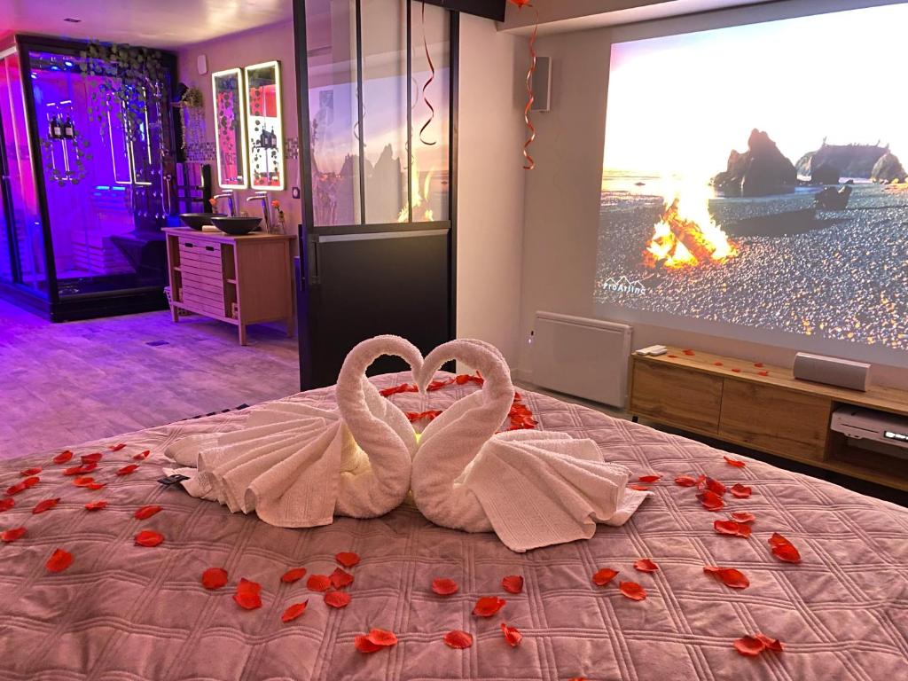 deux cygnes assis sur un lit dans une chambre dans l'établissement BIOTY CHILL & SPA, au Blanc-Mesnil