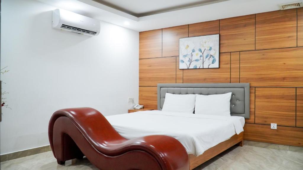 a bedroom with a bed and a leather chair at New Sun Hotel Phu Nhuan in Ho Chi Minh City