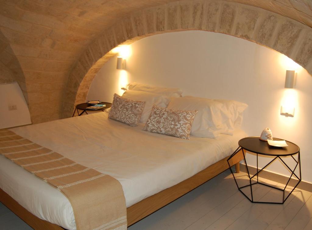 ein Schlafzimmer mit einem großen weißen Bett mit zwei Tischen in der Unterkunft Amalò Guest House in Bari