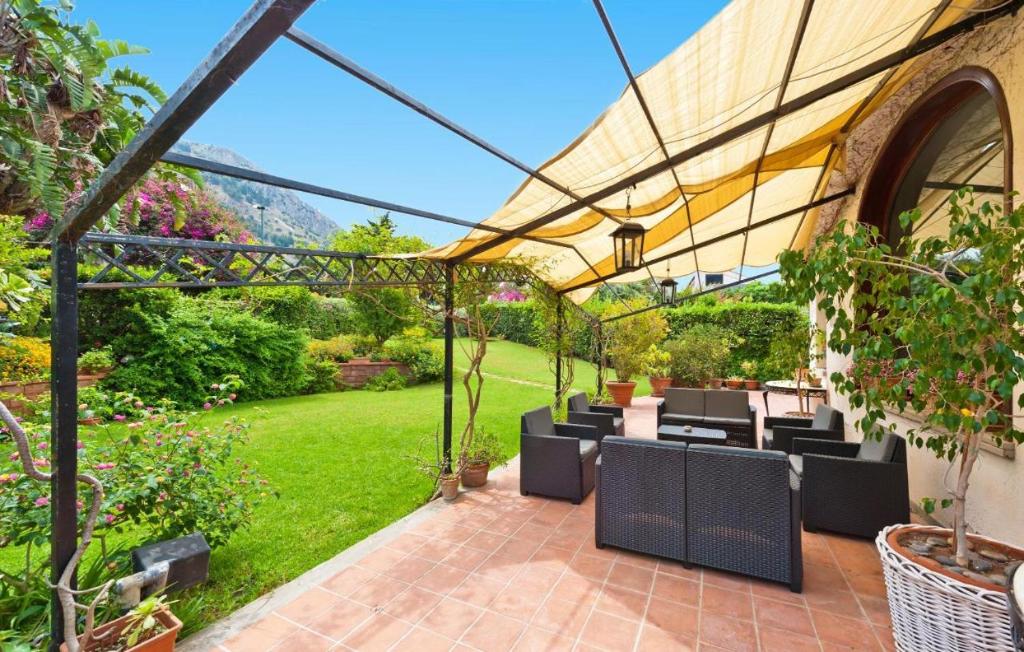 een patio met tafels en stoelen onder een pergola bij Bouganville Home Mondello in Mondello