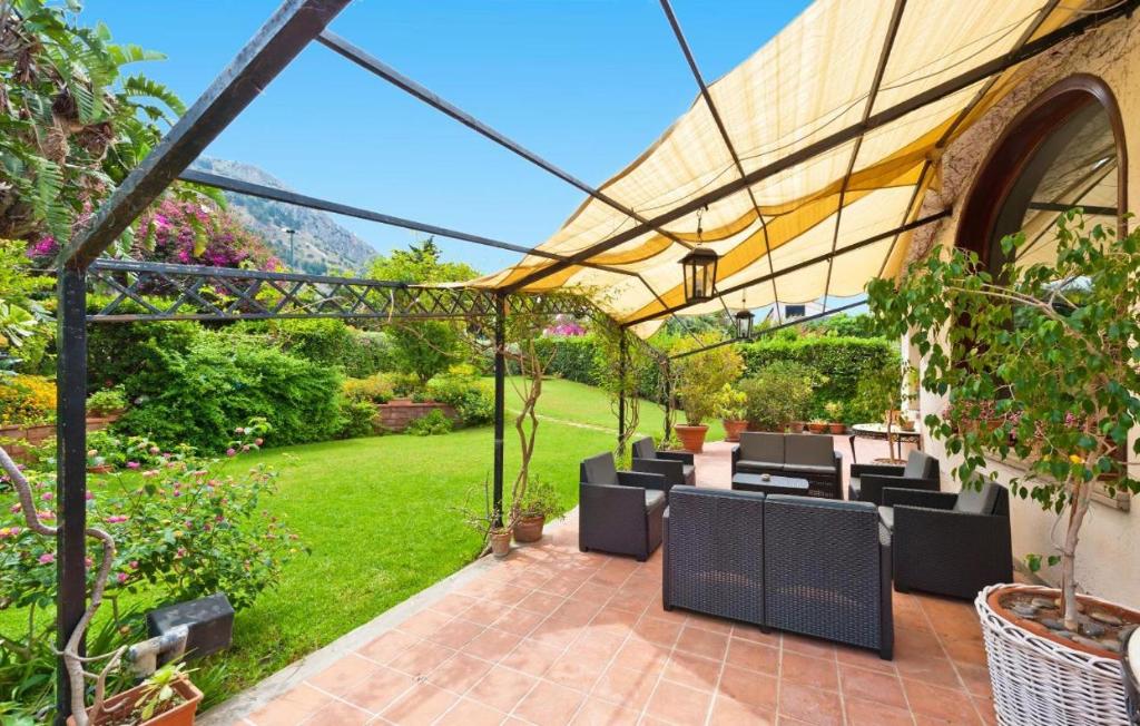 a patio with tables and chairs under a pergola at Bouganville Home Mondello in Mondello