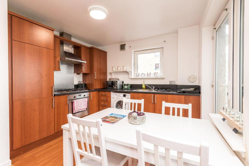 een keuken met een witte tafel en witte stoelen bij Modern Spacious 3 Bedroom City Centre Apartment - Free Parking - Private Balcony in Edinburgh