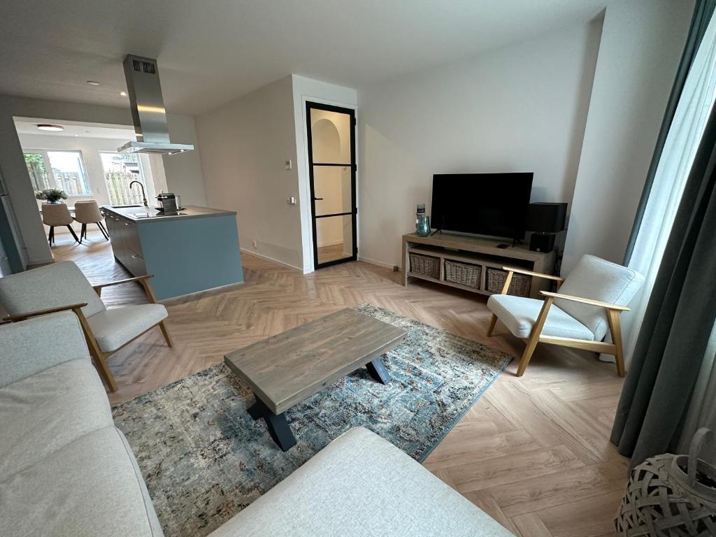 a living room with a couch and a table and a tv at Casa de Schans - 6 persoons vakantiehuis in Landgraaf