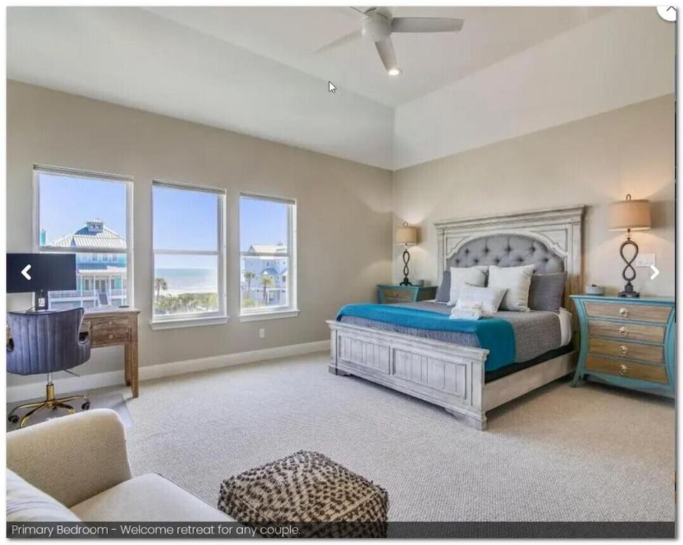 a bedroom with a bed with a blue bedspread and windows at SEAFOAM - Beautiful Luxury Beachside Village Home - Breathtaking Ocean Views- Full Reno in Galveston