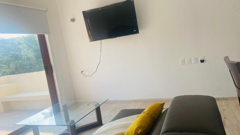 salon z kanapą i telewizorem na ścianie w obiekcie Luana suites- Suite Koya w mieście Zihuatanejo