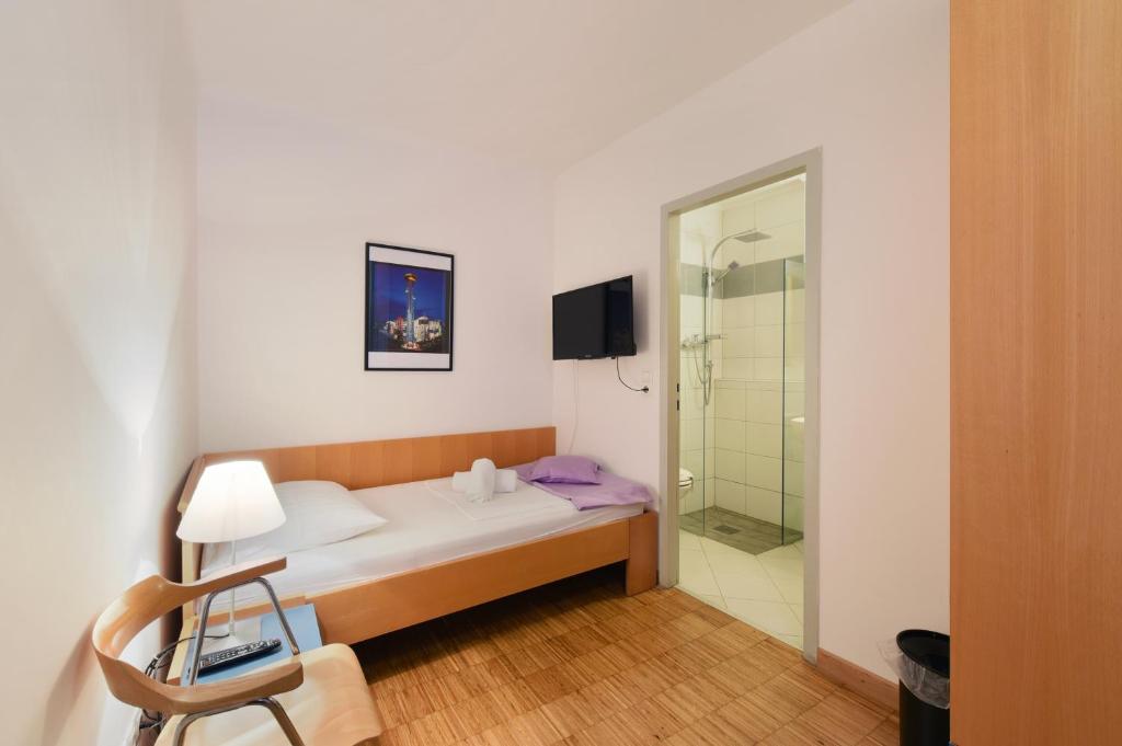 a bedroom with a bed and a glass shower at Hotel Korotan in Vienna