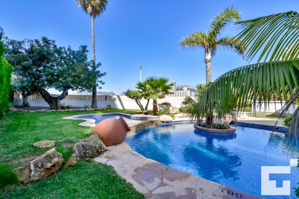 a swimming pool in a yard with palm trees at Apartamento Realet 1F - Grupo Turis in Calpe