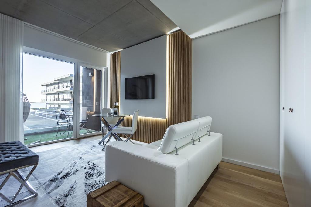 uma sala de estar com um sofá branco e uma televisão em Apartamento Vista Mar em Canidelo