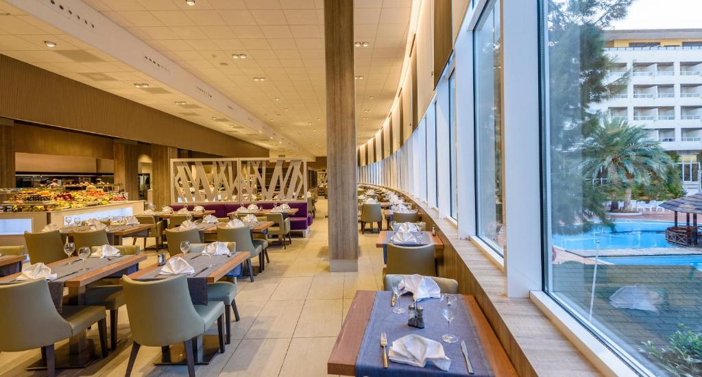 a restaurant with tables and chairs and a large window at Estival Park Silmar in La Pineda