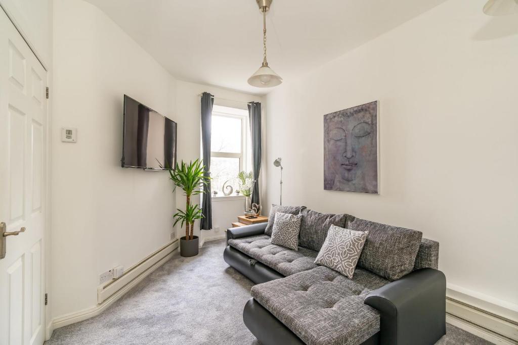 ein Wohnzimmer mit einem Sofa und einem TV in der Unterkunft Charming 1 Bedroom Apartment - Edinburgh in Edinburgh