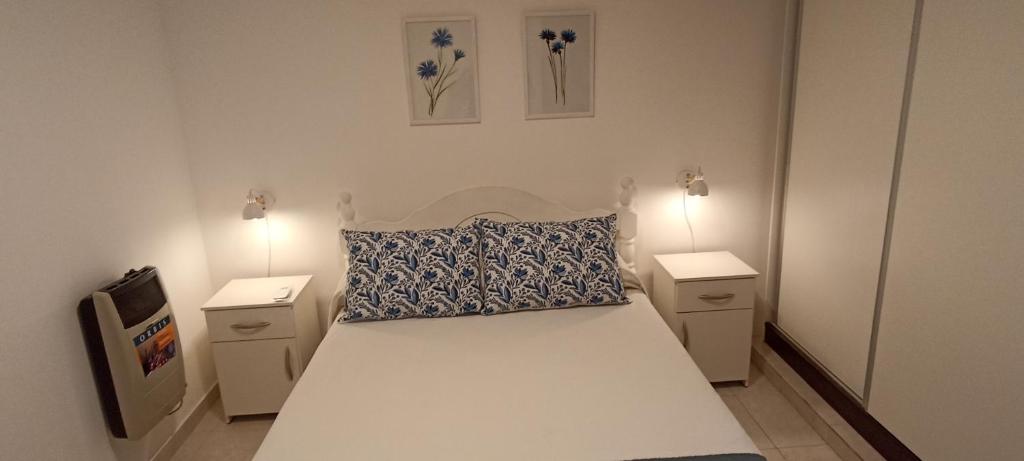 ein Schlafzimmer mit einem weißen Bett und zwei Nachttischen in der Unterkunft ALOJAMIENTO LA ESTACIÓN in Gualeguaychú