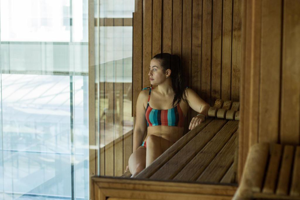 a woman in a bikini sitting in a sauna at Estival Park Silmar in La Pineda