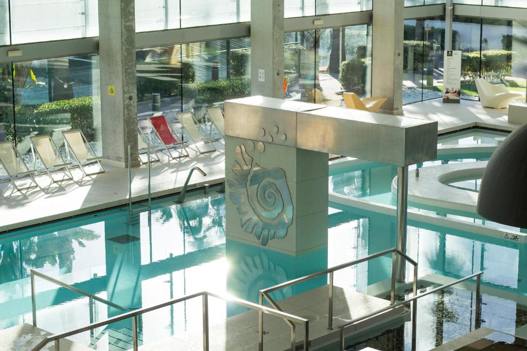 a large swimming pool in a building with chairs at Estival Park Silmar in La Pineda