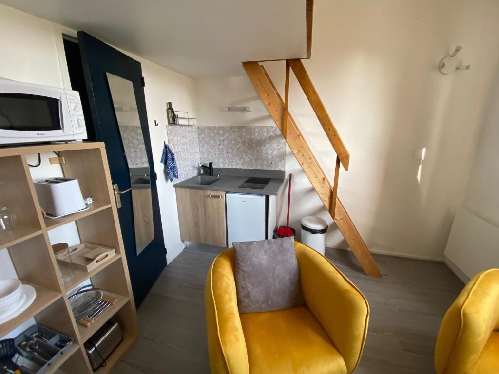 a living room with a yellow chair and a kitchen at Immeuble Les Perdrix in Quimper