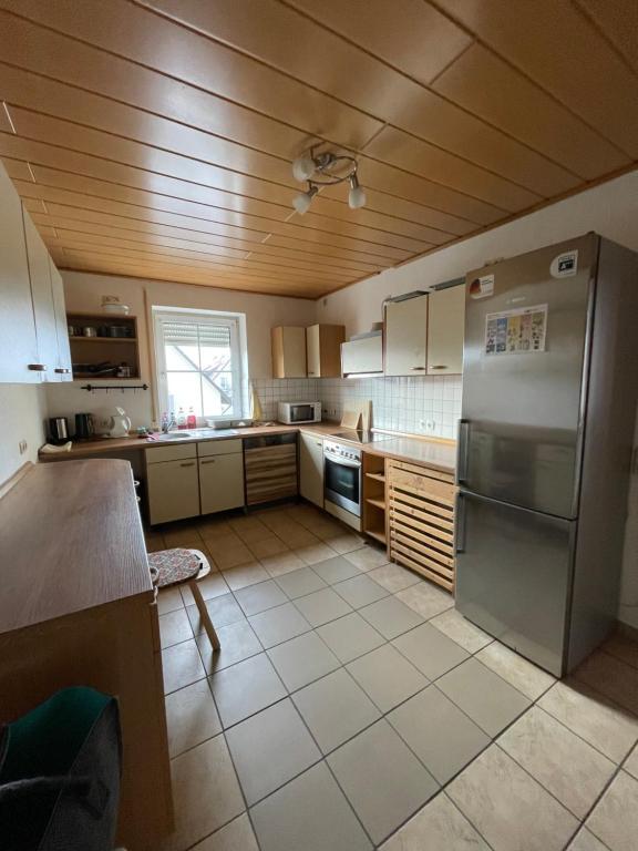 kuchnia z lodówką ze stali nierdzewnej i drewnianym sufitem w obiekcie Wohnung für Monteure in Unterallgäu 