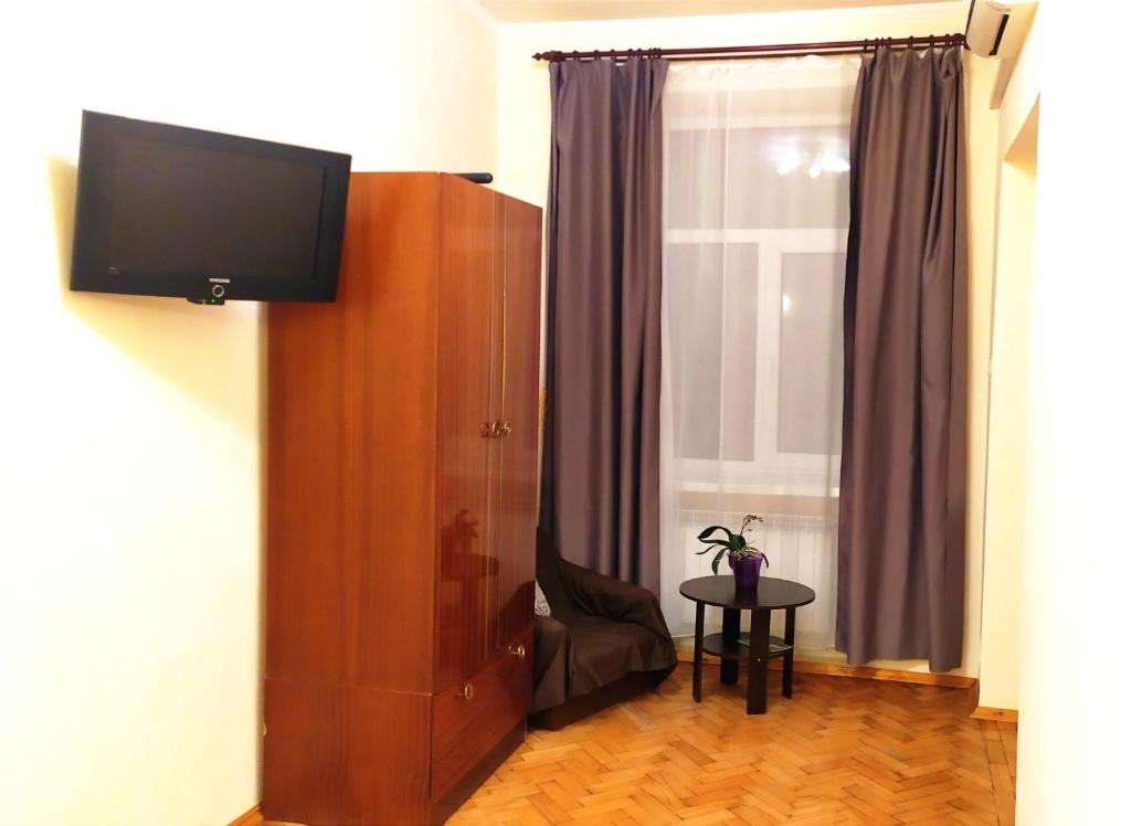 um quarto com uma televisão, uma cadeira e uma janela em Центр Свободи em Lviv