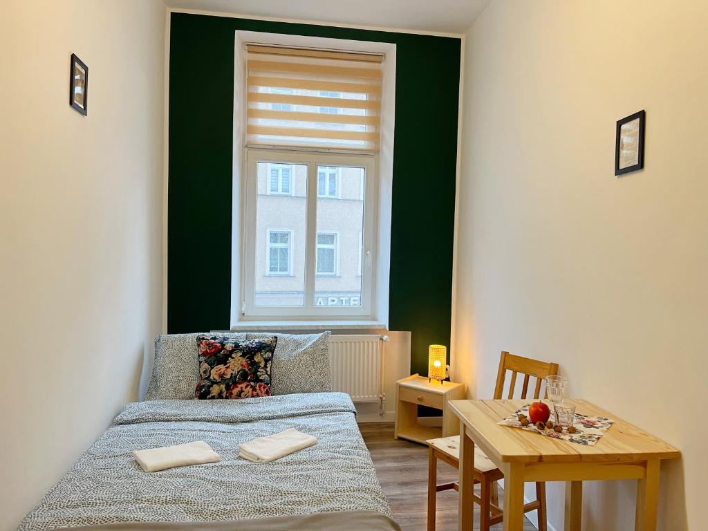 een slaapkamer met een bed, een tafel en een raam bij Noclegi Pan Tadeusz in Wałbrzych