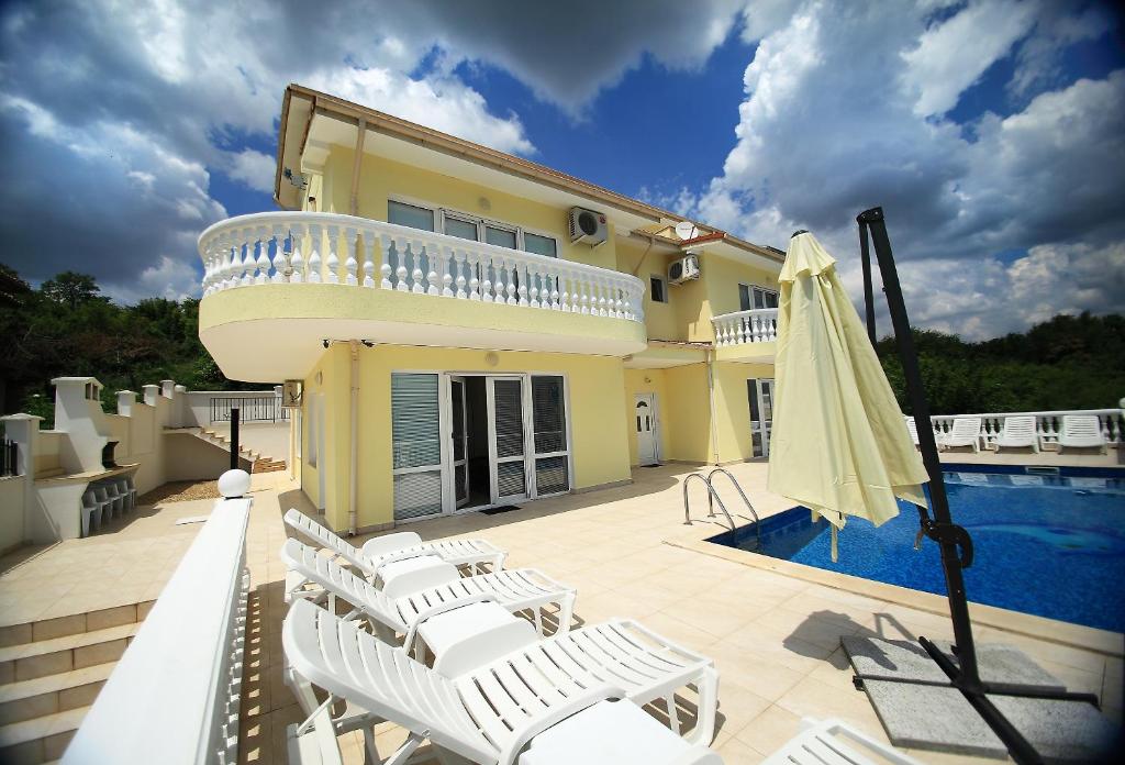 a house with a pool and chairs and a umbrella at Villa Sorento Italian NeoClassica in Balchik