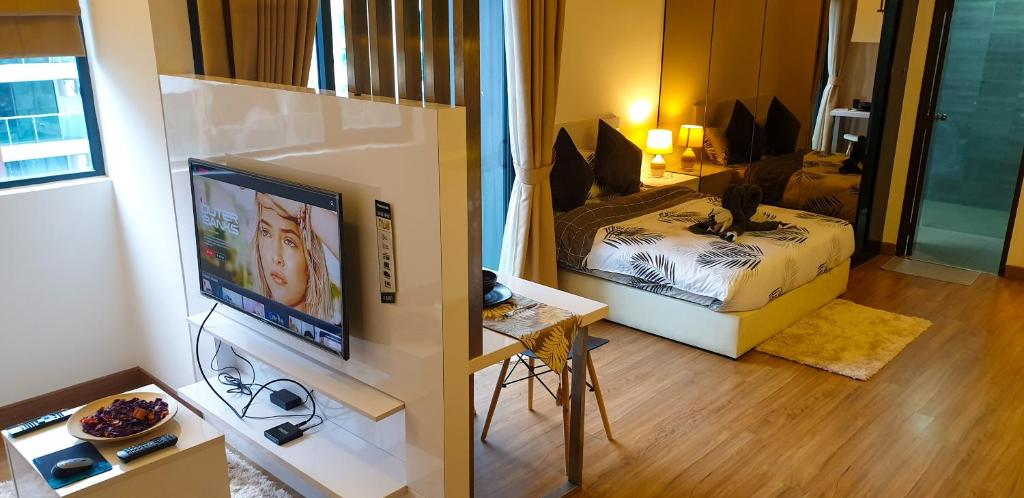 a living room with a television and a bedroom at Eshue Designer Suites @ Simfoni Towers in Cheras