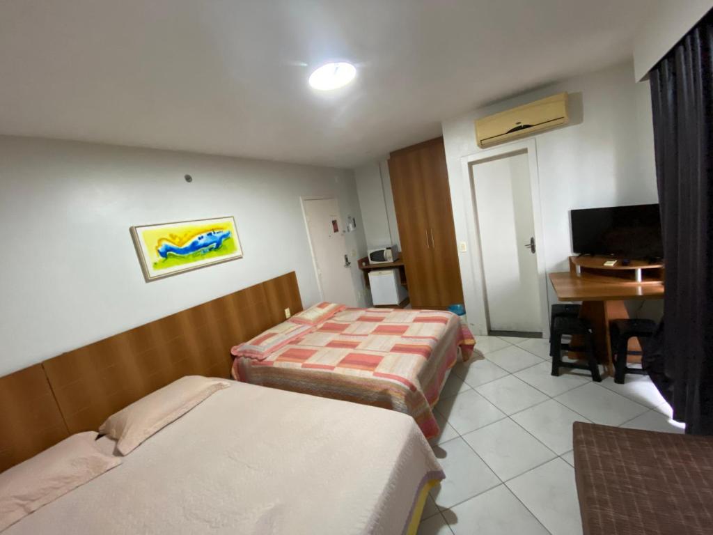 a hotel room with two beds and a desk at Locação Caldas Novas 1105 in Caldas Novas