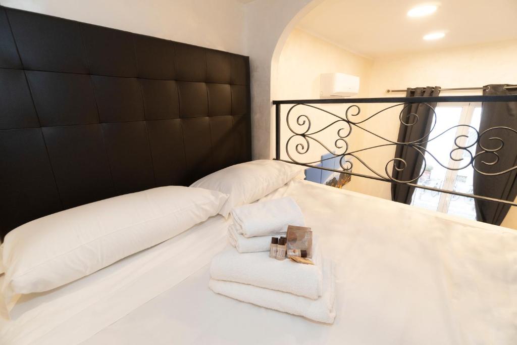 łóżko z białymi poduszkami i czarnym zagłówkiem w obiekcie POPOLO PEN 56 Apartament w Rzymie