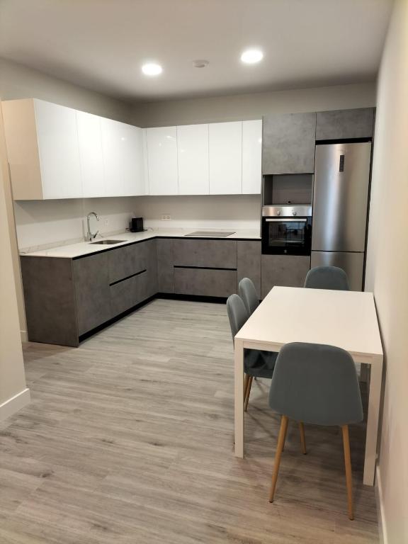 eine Küche mit weißen Schränken sowie einem Tisch und Stühlen in der Unterkunft Apartamentos Kai Santurtzi in Santurce