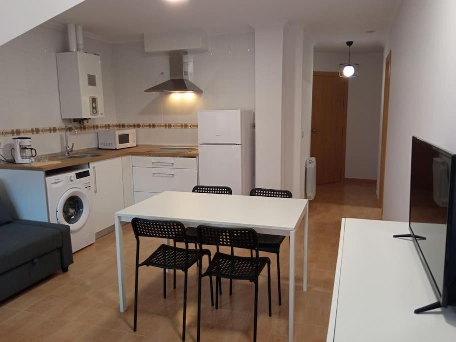una cucina con tavolo e sedie bianchi in una stanza di Loft nuevo a Pontevedra