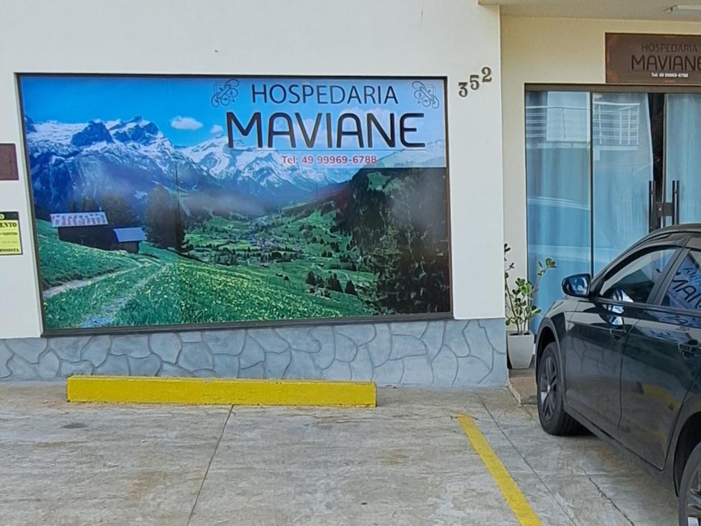 um sinal na lateral de um edifício com um carro estacionado na frente em Hospedaria Maviane Executive em Treze Tílias