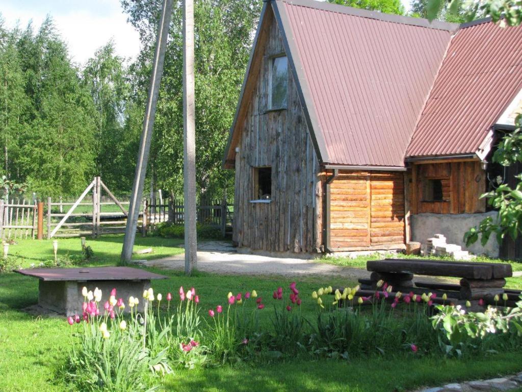 uma cabana de madeira com flores à frente em Kõrtsimaja em Myza Kastre