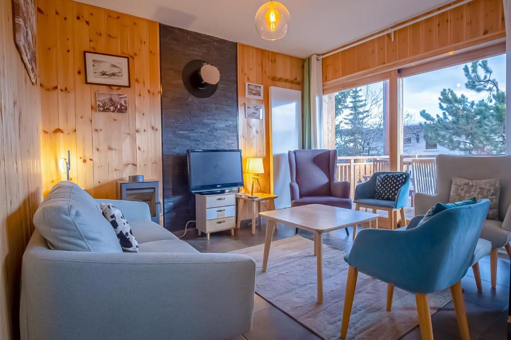 a living room with a couch and chairs and a tv at Spacious apartment with terrace - Alpe d'Huez - Welkeys in LʼHuez